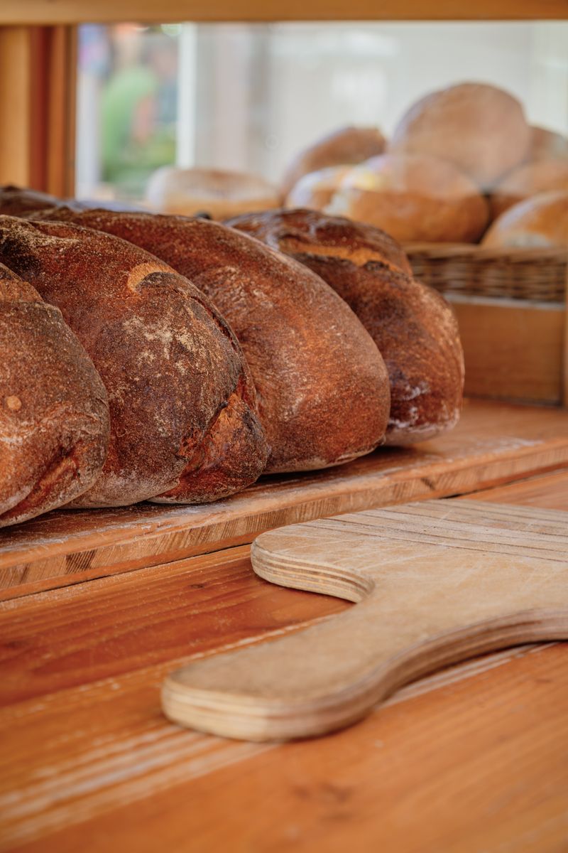 Close-up of freshly baked bread loaves on a wooden table in a bakery setting.